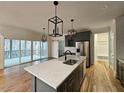 Open kitchen featuring gray cabinets, stainless steel appliances, hardwood floors, and an island with a sink at 5491 Silk Hope Gum Springs Rd, Siler City, NC 27344