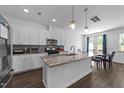 Modern kitchen featuring white cabinets, a granite island, stainless steel appliances, and an eat-in breakfast area at 608 Creekway Dr, Fuquay Varina, NC 27526