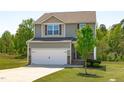 Two-story home features a two-car garage, neutral siding, and a well-maintained front yard with a young tree at 80 Doonbeg Dr, Fuquay Varina, NC 27526