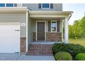 Inviting front porch with stone accents, brick steps, and decorative shrubs at 80 Doonbeg Dr, Fuquay Varina, NC 27526