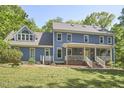 Inviting two-story home featuring classic blue siding, a covered porch, and large windows at 8407 Millers Bnd, Bahama, NC 27503