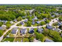 High angle aerial view of suburban neighborhood featuring tree-lined streets and manicured lawns in a residential area at 909 Starkland Way, Holly Springs, NC 27540