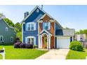 Charming two-story home with blue siding, brick accents, a well-manicured lawn, and a welcoming yellow front door at 909 Starkland Way, Holly Springs, NC 27540