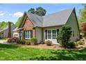 A charming home with a brick chimney, well-kept lawn, and mature trees, offering great curb appeal at 910 S Third St, Mebane, NC 27302