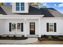 Inviting front entrance with black door, trimmed windows, and manicured landscaping at 9200 Otter Ct, Middlesex, NC 27557