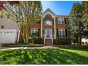 A beautiful two-story brick home with white trim, showcasing a well-maintained lawn and inviting facade at 102 Traviliah Oaks Ln, Cary, NC 27518