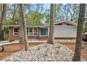 Exterior view of this beautiful home, featuring mature trees, landscaping, and blue front door at 1124 Hardimont Rd, Raleigh, NC 27609