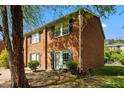 Attractive brick townhome showcasing a side view, complemented by green lawn and shade trees at 115 Coleridge Ct, Carrboro, NC 27510
