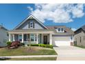 Charming blue home featuring a welcoming front porch, two-car garage, and beautifully landscaped yard at 1208 Steinbeck Dr, Durham, NC 27703
