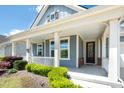 Inviting front porch with white railings, offering a cozy seating area and view of the landscaped yard at 1208 Steinbeck Dr, Durham, NC 27703