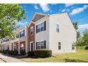 A view of an end unit townhome with light vinyl siding and brick accents and manicured landscaping at 1304 Cozart St # 216, Durham, NC 27704