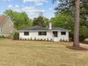 Well-maintained white brick home with a spacious lawn and mature trees, perfect for outdoor enjoyment at 1310 Mayfair Rd, Raleigh, NC 27608