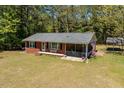 Lovely brick home with a screened-in porch, bench, flag, and a beautifully landscaped yard surrounded by trees at 19461 Nc Highway 210, Angier, NC 27501