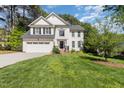Beautiful two-story white home with a well-manicured lawn and a two-car garage on a sunny day at 205 Lippershey Ct, Cary, NC 27513