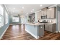 Open-concept kitchen boasting stainless steel appliances, a center island, and hardwood flooring extending to the living room at 226 Mahogany Run, Raleigh, NC 27610