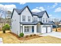 Attractive grey two-story home with a covered porch, three-car garage, and well-maintained landscaping at 2437 Terri Creek Dr, Fuquay Varina, NC 27526
