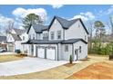 Side view of a grey two-story home with a three-car garage, set on a partially landscaped lot at 2437 Terri Creek Dr, Fuquay Varina, NC 27526