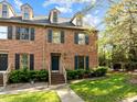 Inviting brick townhome featuring classic blue shutters, dormer windows, and a neatly manicured lawn at 3100 Coachmans Way, Durham, NC 27705
