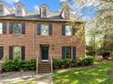 Beautiful brick townhome featuring dormer windows, black shutters, and a manicured lawn at 3100 Coachmans Way, Durham, NC 27705