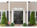 Close-up of an elegant black front door framed by sidelights and decorative trim, with lush landscaping at 406 Sapphire Dr, Durham, NC 27703