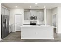 Modern kitchen with gray cabinets, stainless steel appliances, stylish backsplash, and a large center island at 441 White Birch Ln # 66, Angier, NC 27501