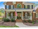 Beautiful brick home with a covered front porch, adorned with the American flag, creating a patriotic welcome at 4513 Touchstone Forest Rd, Raleigh, NC 27612