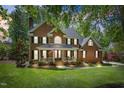 Traditional brick home featuring a covered front porch, manicured lawn, and mature trees at 4513 Touchstone Forest Rd, Raleigh, NC 27612