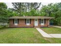 Quaint brick home featuring black shutters, a tidy lawn, and a concrete walkway to the front door at 508 Solar Dr, Raleigh, NC 27610