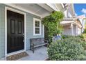 Inviting front porch with a wooden bench, vibrant greenery, and a stylish black front door at 512 Flip Trl, Cary, NC 27513