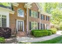 Close-up of stately brick home featuring leaded glass front door and well-manicured landscaping at 5912 Weather Rock Ct, Raleigh, NC 27613