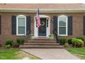 Inviting front entrance with brick steps, an American flag, and black shutters under a clear sky at 705 N Gurney St, Burlington, NC 27215