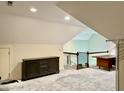 Spacious finished attic area, featuring carpet, a dark wood cabinet, and a desk at 84 Dogeye Rd, Benson, NC 27504