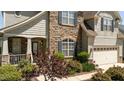 Charming home exterior with stone accents, a covered porch, and lush landscaping at 9212 Linslade Way, Wake Forest, NC 27587