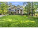 Beautiful brick home with grand columns, lush lawn, and mature trees creating a serene landscape at 104 Arcadia Ln, Chapel Hill, NC 27514