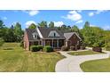 An angled view of a brick house showing lush landscaping and a curved driveway leading up to the front at 121 Westchase Run, Sanford, NC 27330