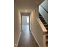 Hallway with wood floors leading to a staircase with gray carpeting, and an open entryway at 147 Landon Pl, Roxboro, NC 27573