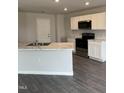 Kitchen with stainless steel appliances, white cabinets, an island, and dark floors at 173 Lillian Ct, Roxboro, NC 27573