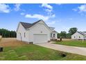 Side view of a one-story new construction home featuring an attached garage, concrete driveway, and manicured lawn at 203 Sourgum Ct, Zebulon, NC 27597
