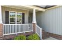 Close up of the home's entryway and cozy front porch with white railing and brick accents at 241 Connelly Way, Zebulon, NC 27597