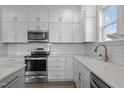 Well-lit kitchen featuring white cabinets, stainless steel appliances, quartz countertops, and subway tile backsplash at 241 Connelly Way, Zebulon, NC 27597