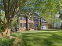 Beautiful two-story brick home with mature trees, lush green lawn, and an attached garage at 308 Sunset Creek Cir, Chapel Hill, NC 27516