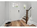Bright entryway with hardwood floors, white door, and staircase with wood handrail at 3908 Booker Ave, Durham, NC 27713