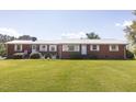 Brick ranch featuring a metal roof, manicured lawn, and beautiful landscaping at 481 Firetower Rd, Louisburg, NC 27549