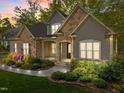Inviting home at twilight featuring a stone facade, a cozy front porch, and professionally landscaped yard at 4924 Theys Rd, Raleigh, NC 27606