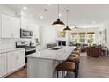 Bright open-concept kitchen featuring a large granite island with bar seating, stainless appliances and an open view to the living room at 716 Ben Ledi Ct, Raleigh, NC 27603
