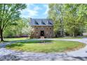 Traditional brick home with dormer windows surrounded by lush green trees and mature landscaping at 8120 Stillbreeze Dr, Fuquay Varina, NC 27526