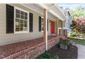 Inviting front porch with a brick floor and a vibrant red front door at 904 Emory Ln, Raleigh, NC 27609
