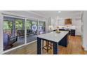Bright kitchen features a large center island, a view to the screened porch, modern appliances and dark blue and white cabinetry at 1005 Thorncroft Ln, Apex, NC 27502