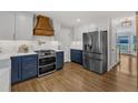 Modern kitchen with stainless steel appliances, double oven range, custom range hood, and blue base cabinets at 1005 Thorncroft Ln, Apex, NC 27502