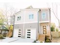Two-story townhome featuring a light gray exterior with white garage doors and wood stairs at 109 S Plum St, Durham, NC 27703
